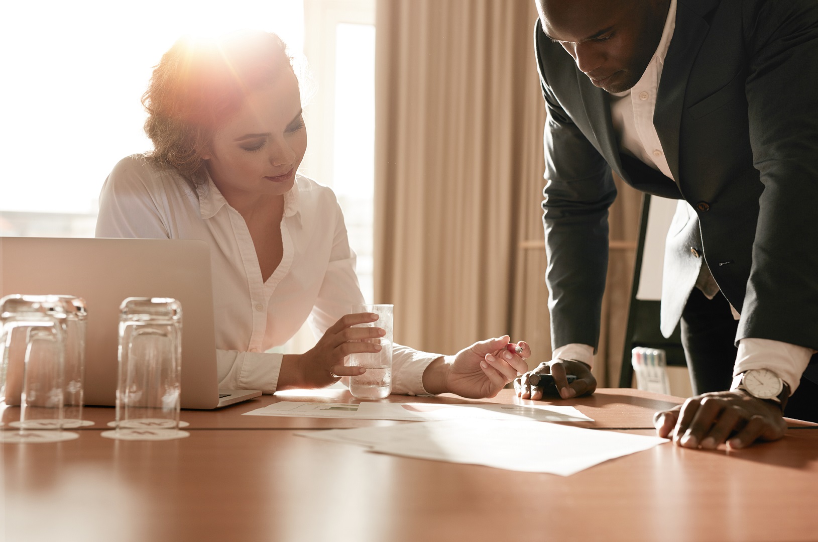 Two young business colleagues working on some business ideas. Entrepreneurs analyzing business reports on conference table.